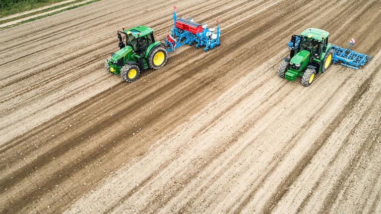 A&ccedil;ık alanda iki John Deere 6M trakt&ouml;r&uuml;. Bir tanesi Monsomen mibzer &ccedil;ekiyor.  Diğeri Lemken tohum yataklı kombinasyon &ccedil;ekiyor