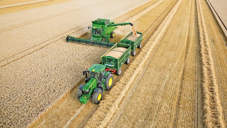 Trakt&ouml;r&uuml;n &ccedil;ektiği ikili r&ouml;morka buğday boşaltan John Deere S Serisi bi&ccedil;erd&ouml;ver