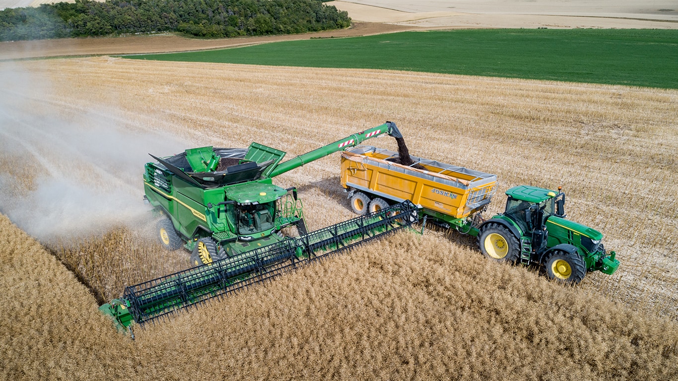 John Deere trakt&ouml;r&uuml;n &ccedil;ektiği tahıl arabasına kolza tohumu boşaltan John Deere X Serisi bi&ccedil;erd&ouml;ver