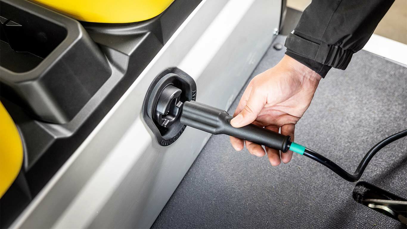 Şarj kablosunu bir John Deere Gator GS elektrikli hizmet aracının yan bağlantı noktasına takan el.