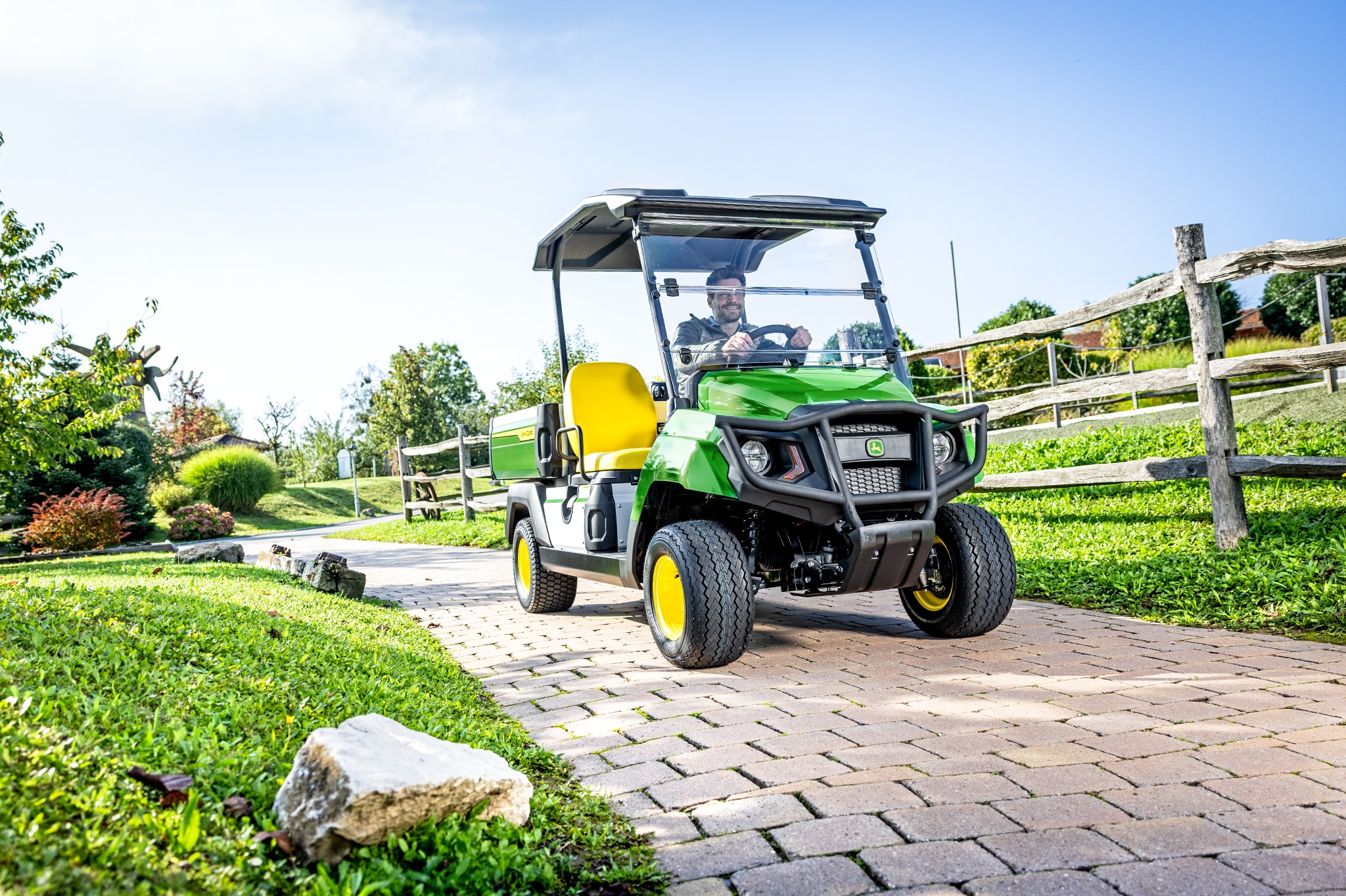 Peyzajlı bir alanda asfaltlı bir yolda giden Gator GS hizmet aracı