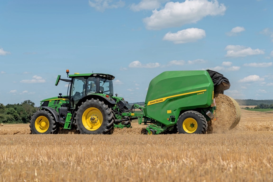 Saman tarlasında bir John Deere 6R 150 tarafından çekilen John Deere V452R balya çıkarıyor