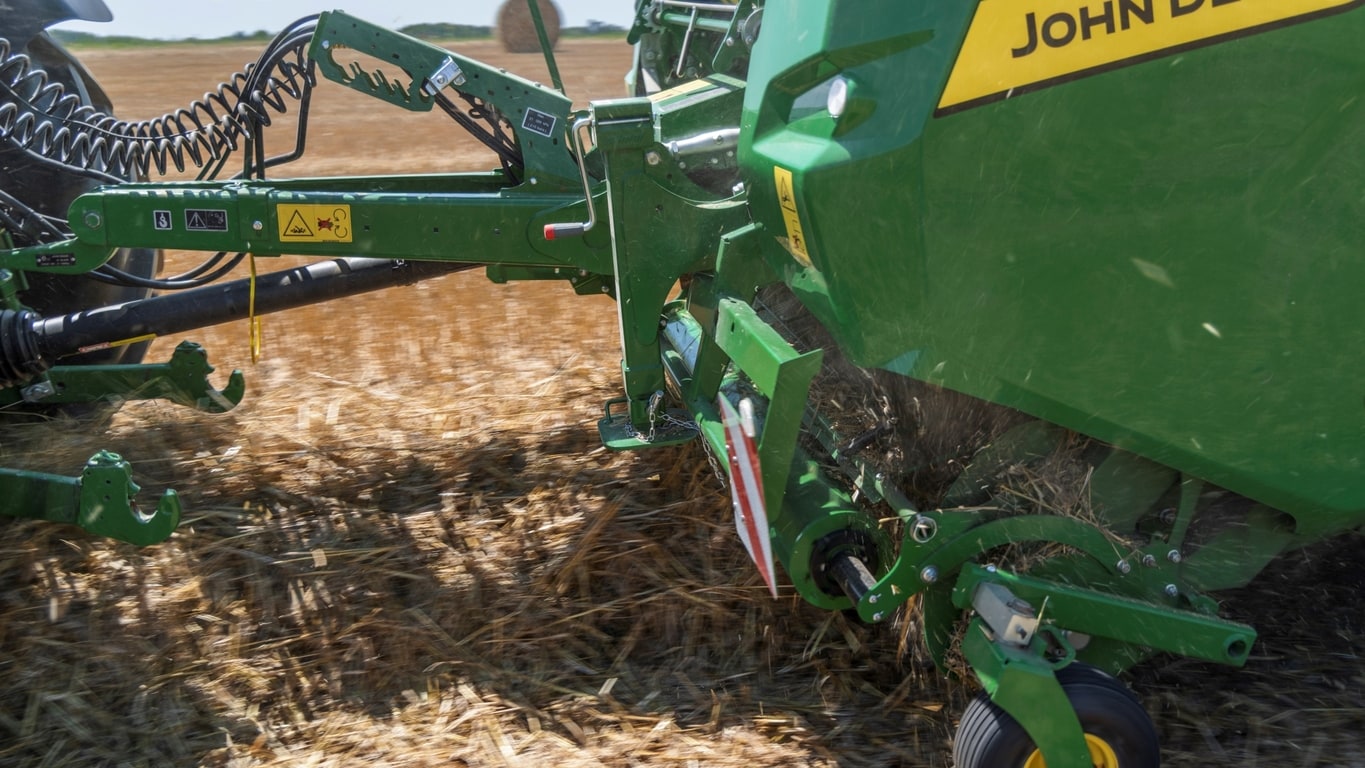 Bir John Deere VR balya makinesinin yüksek kapasiteli toplayıcısı büyük bir saman namlusu alıyor