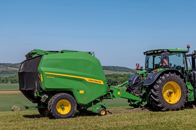 Bir John Deere 6R 185 traktör tarafından çekilen John Deere V462R saman balyalama yapıyor